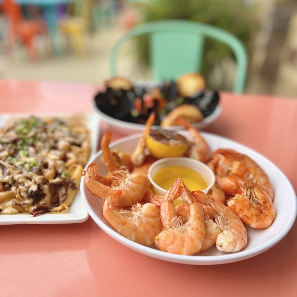 Fried seafood beside barbecue on white plates.